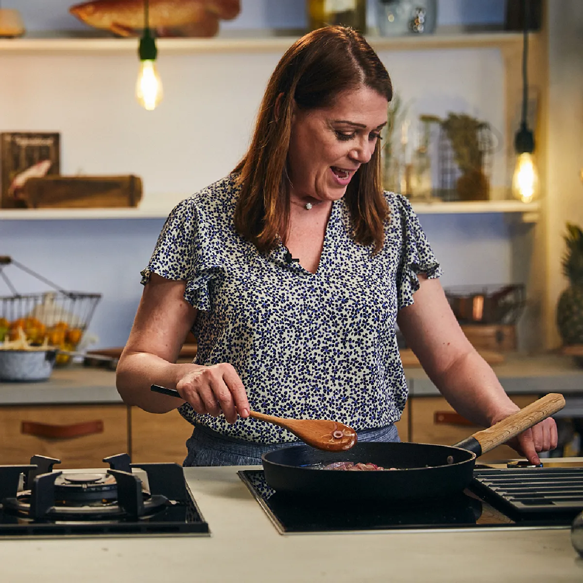 Donna cucina in una cucina accogliente con vari utensili da cucina e ingredienti sul banco.