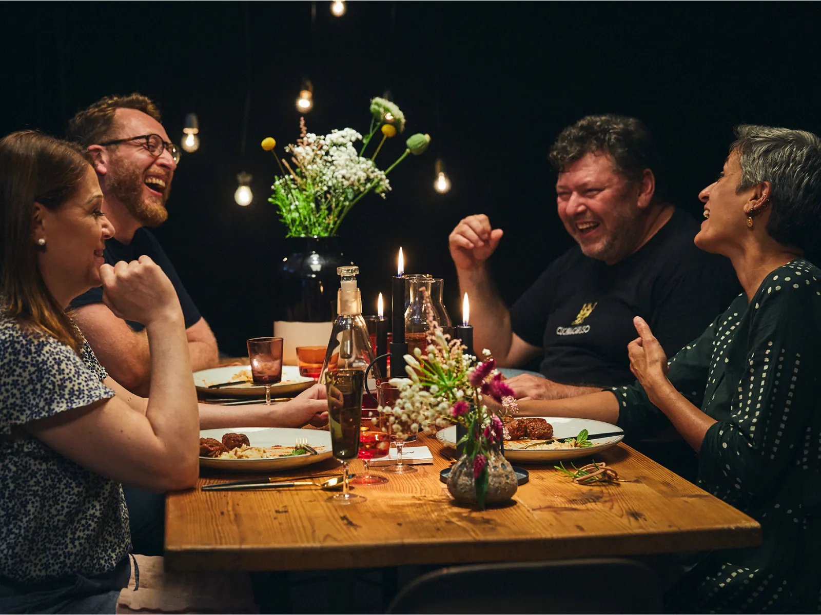 Cena con amici, risate, cibo, bevande e un'atmosfera accogliente.