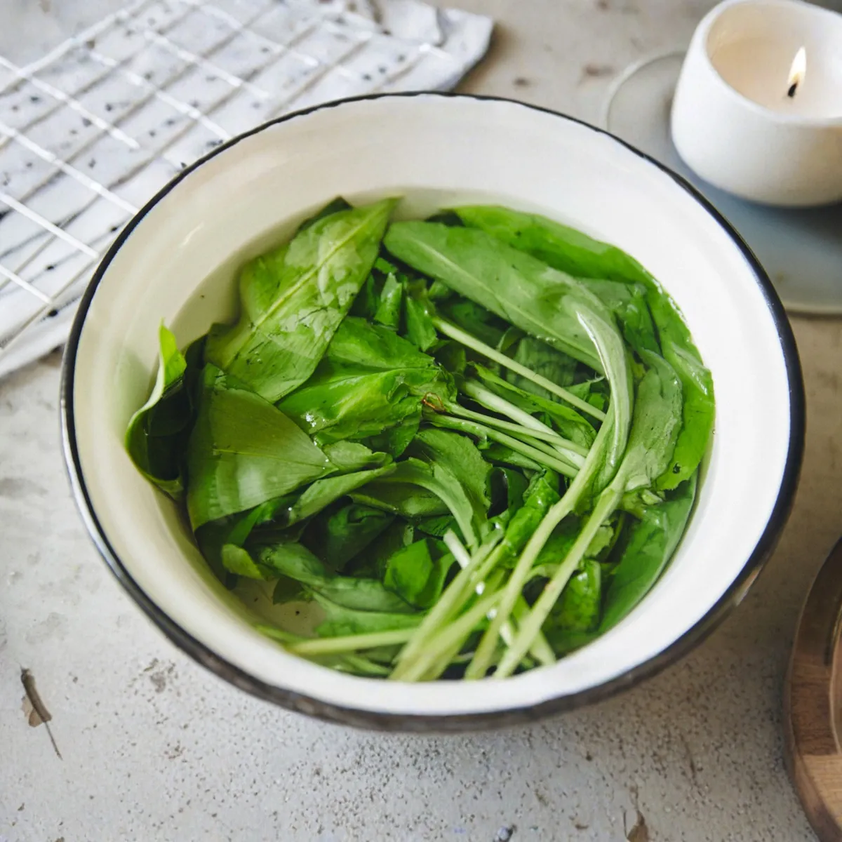 Primo piano di erbe aromatiche fresche a foglia verde immerse in una ciotola bianca piena d'acqua.