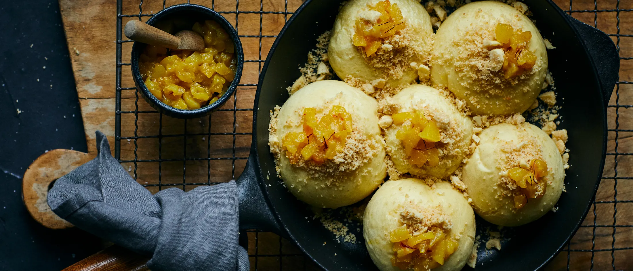 Gnocchi di pasta lievitata rotondi con topping di briciole e pezzi di frutta in padella nera