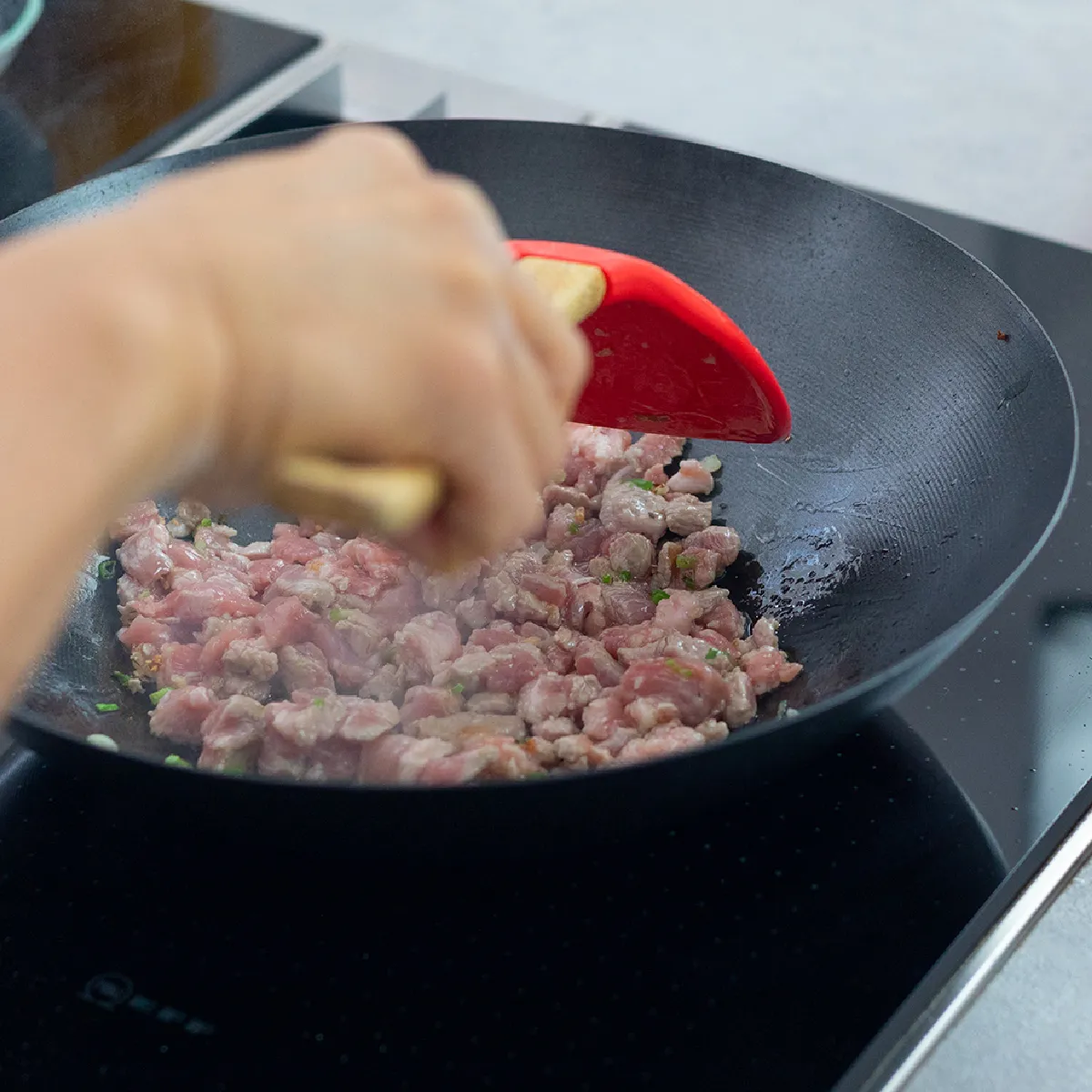 Saltare in padella maiale, kimchi e noodles in un wok mentre si prepara il ripieno per i panini al vapore