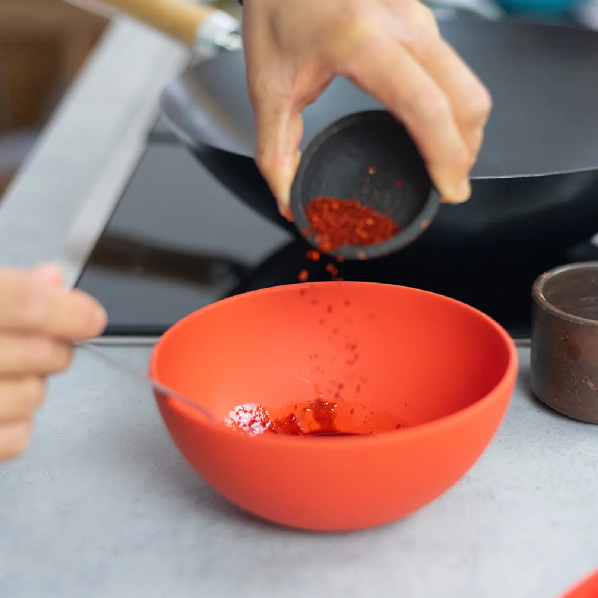 Mani che impastano la pasta su un bancone della cucina, con ciotole e utensili nelle vicinanze, durante la preparazione del pane