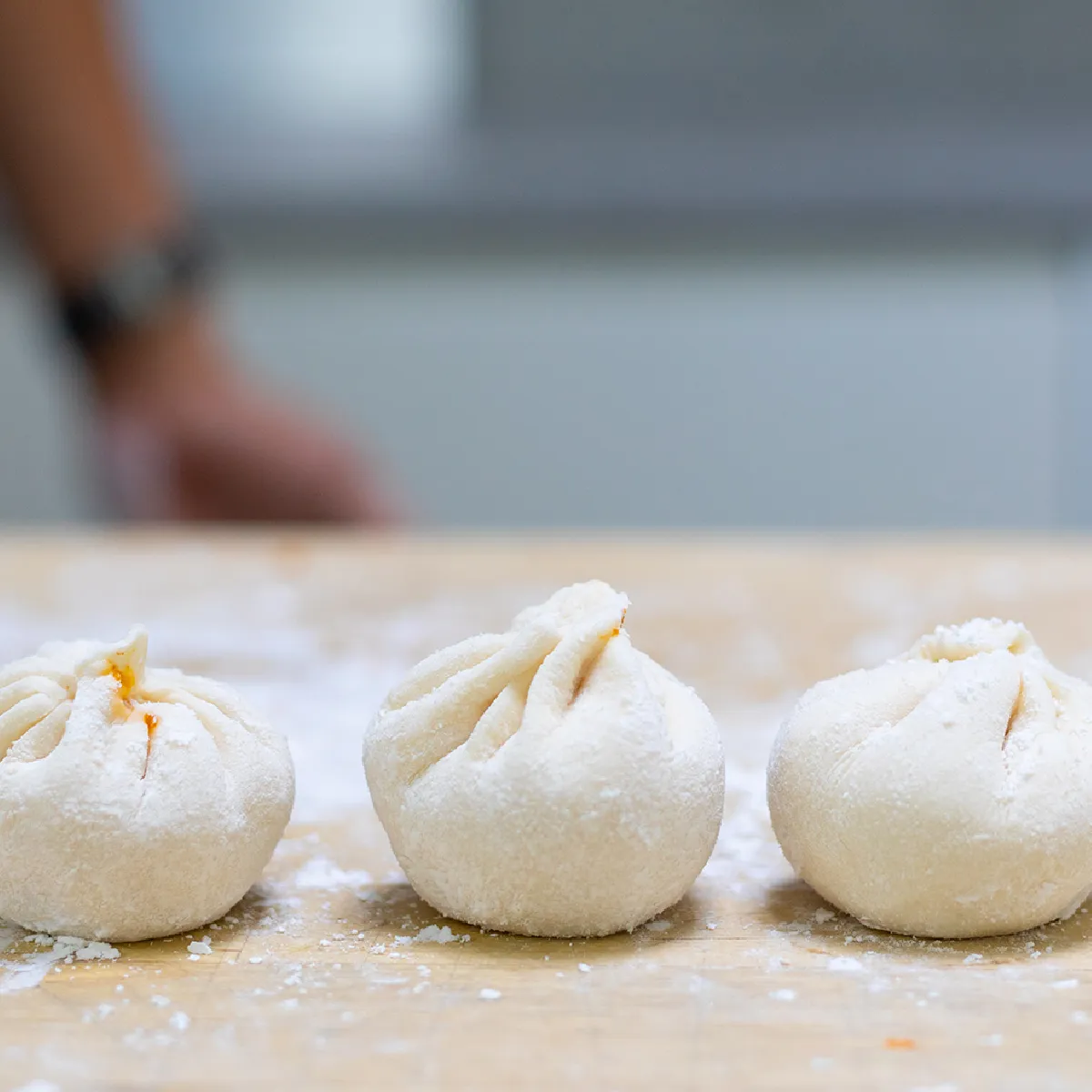 Panini al vapore ripieni di maiale caramellato e kimchi, guarniti con semi di sesamo ed erba cipollina