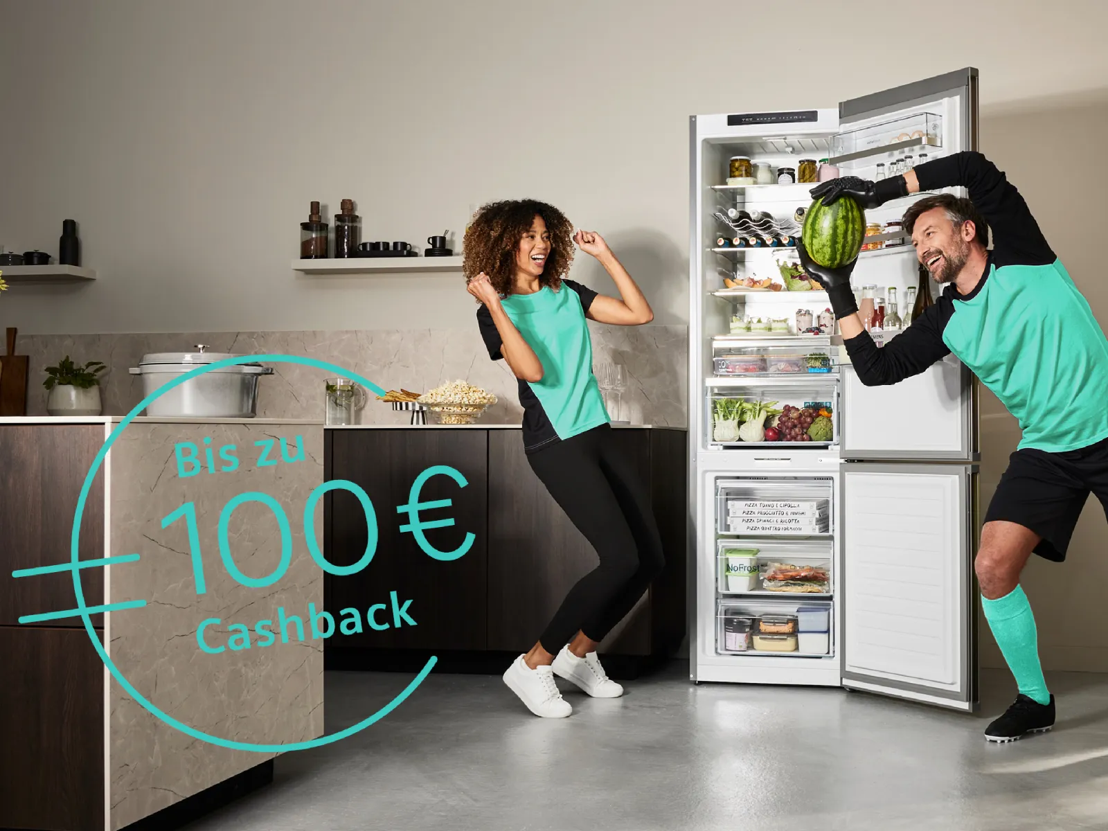 Zwei Personen stehen vor einem Siemens Kühlschrank und stellen Fußballspieler dar.