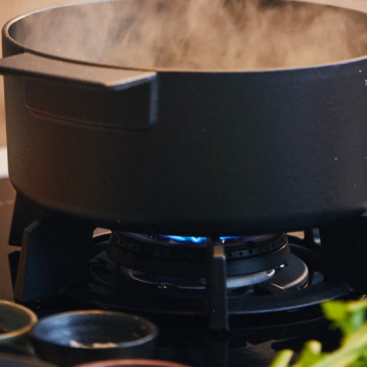 Vaporizzatore su stufa a gas, circondato da erbe fresche, pronto per la cottura.