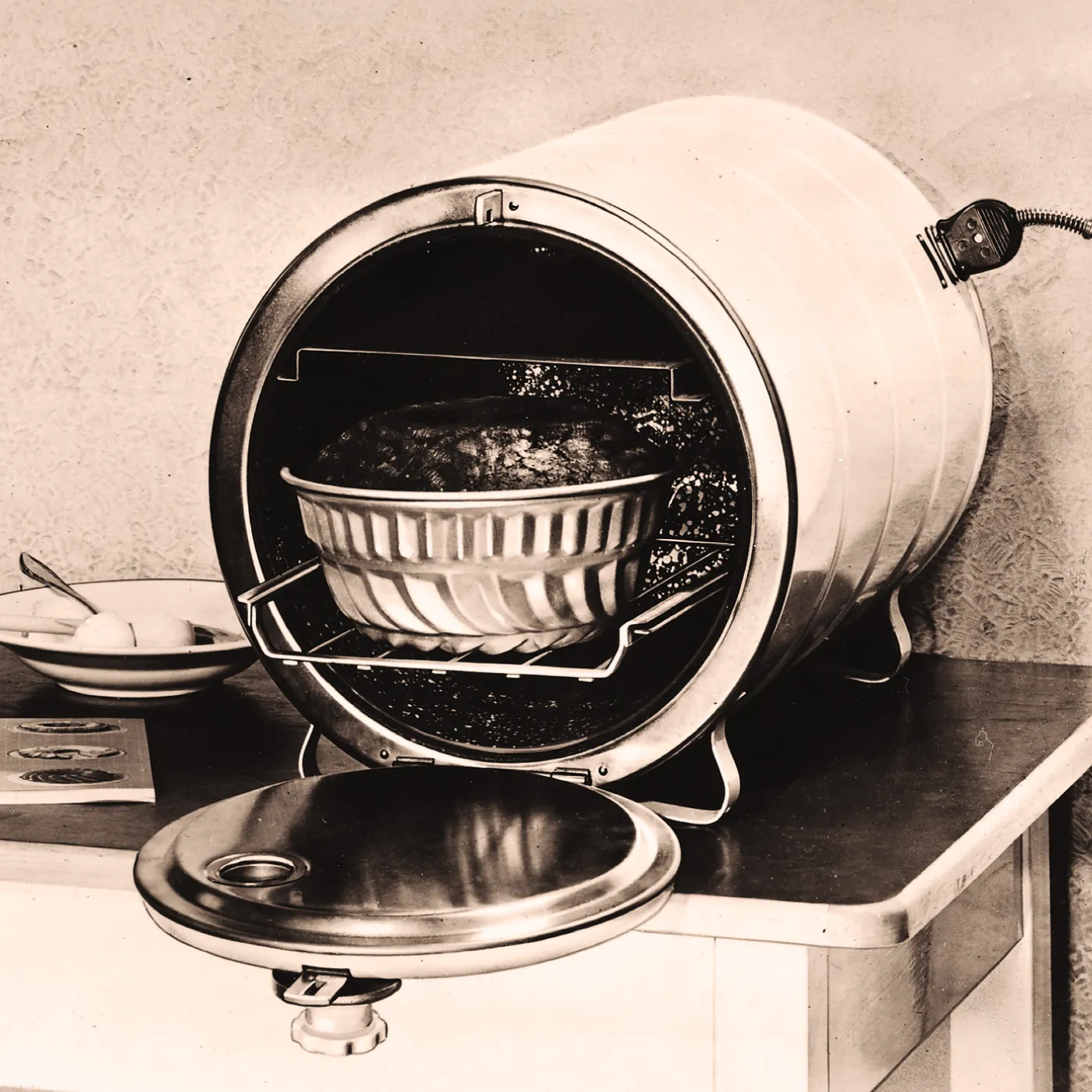 A vintage barrel-shaped oven with a dish inside, on a countertop.
