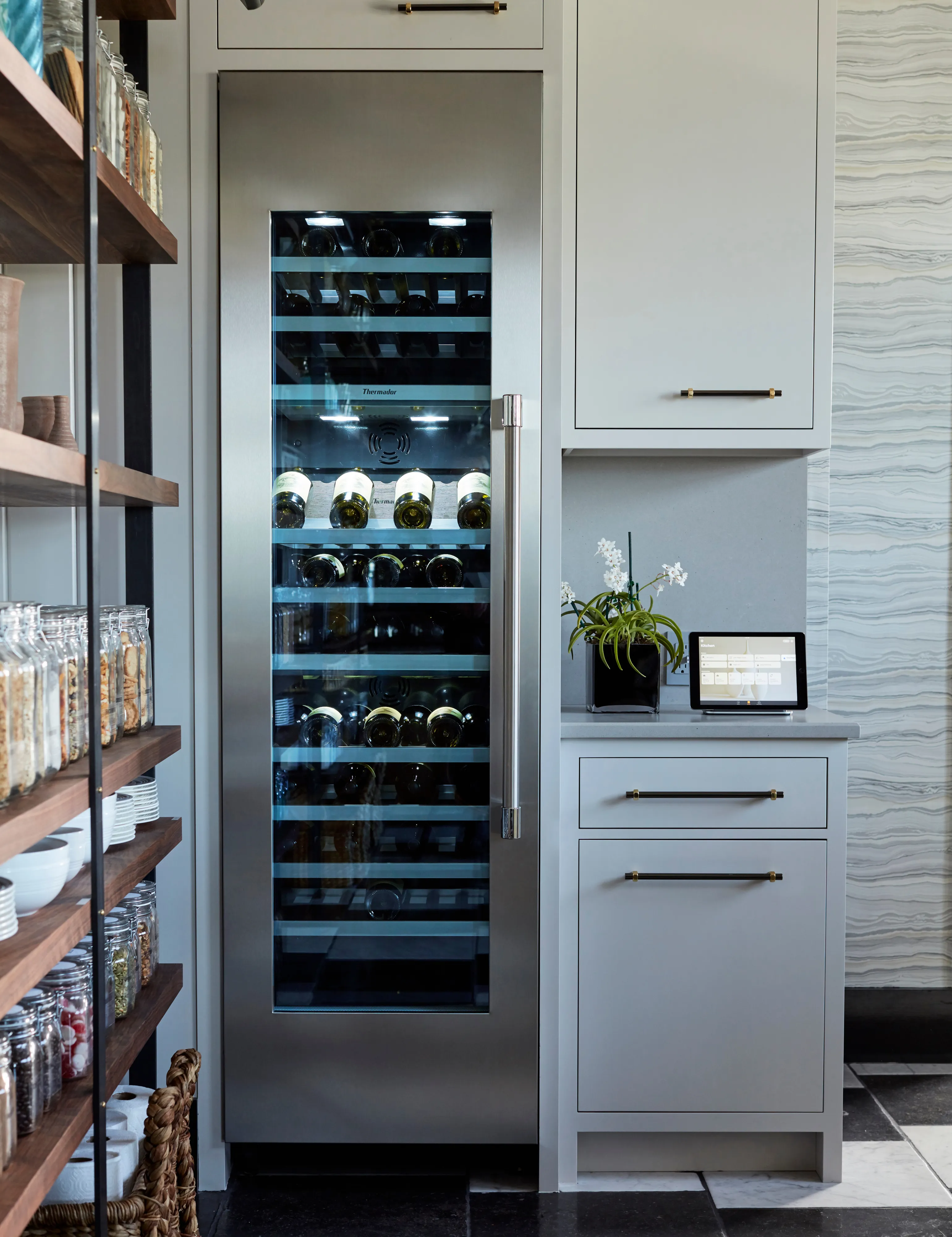 Tall stainless-steel built-in wine refrigerator with a glass door and interior lighting