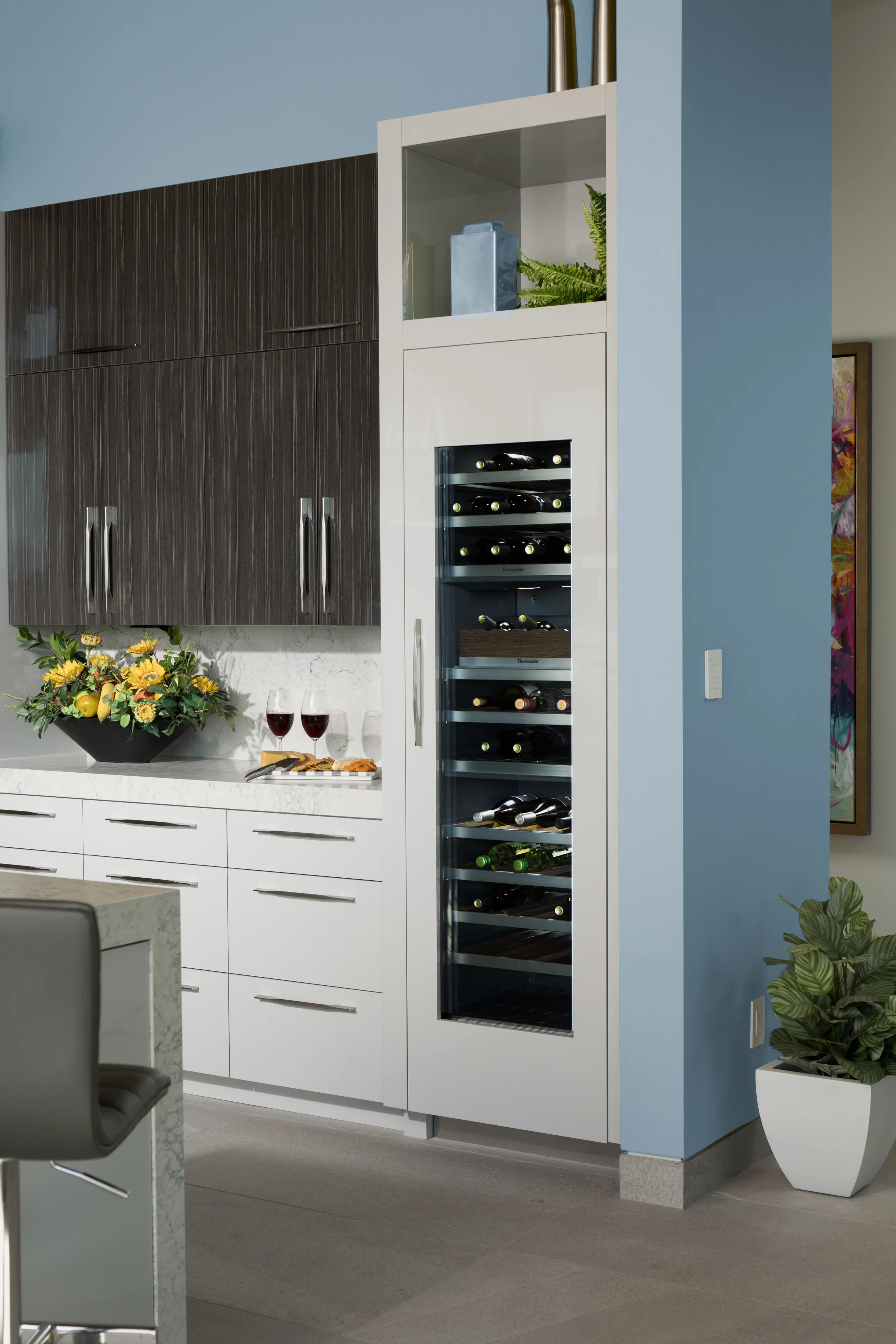 Tall, narrow built-in wine refrigerator with a glass door and interior lighting displaying horizontal bottles