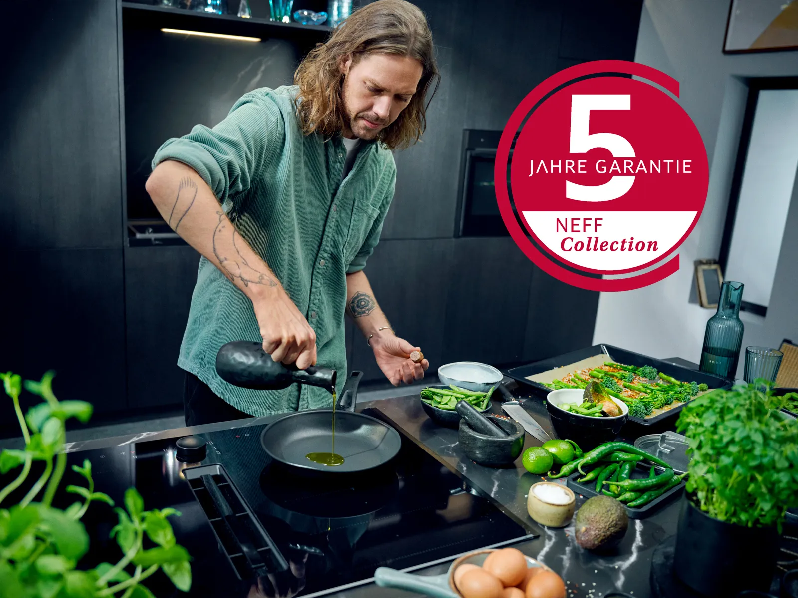 Mann kocht in NEFF Collection Küche mit Kochfeld und 5 Jahre Garantie Badge für Küchengeräte