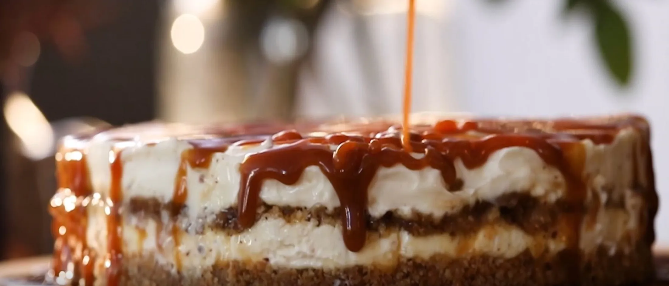 Κρεμώδες τσιζκέικ με σάλτσα καραμέλας, σε ξύλινο τραπέζι με απαλό φωτισμό. 