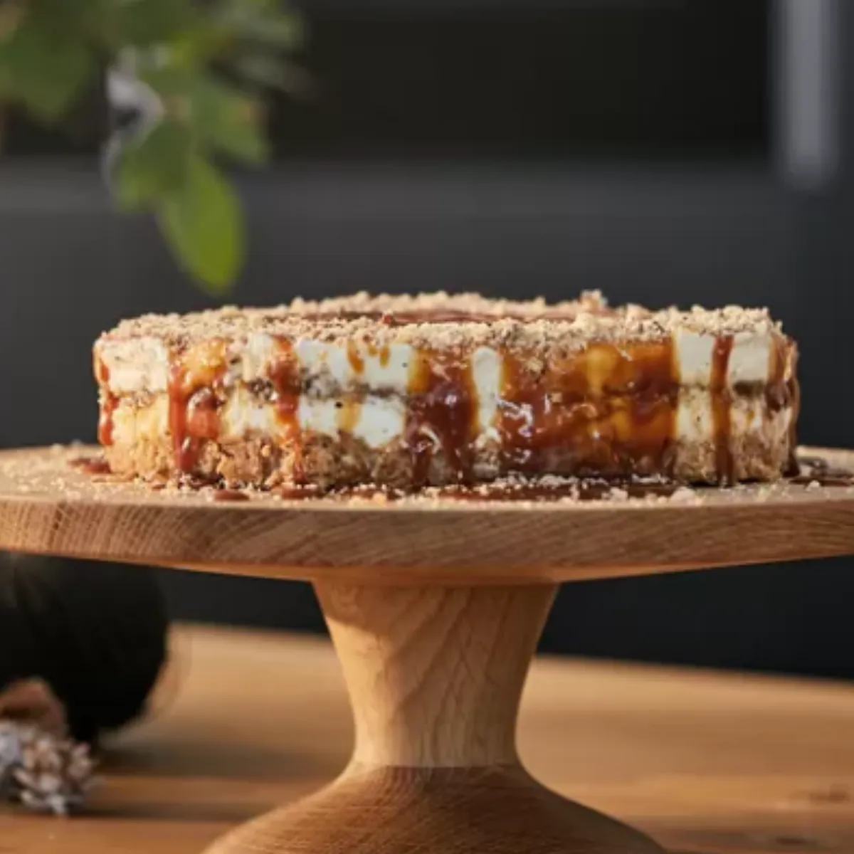 Ράστιτς ξύλινος πάγκος με ένα στρωμένο κέικ με γλάσο και διακόσμηση, που περιβάλλεται από διακόσμηση διακοπών.