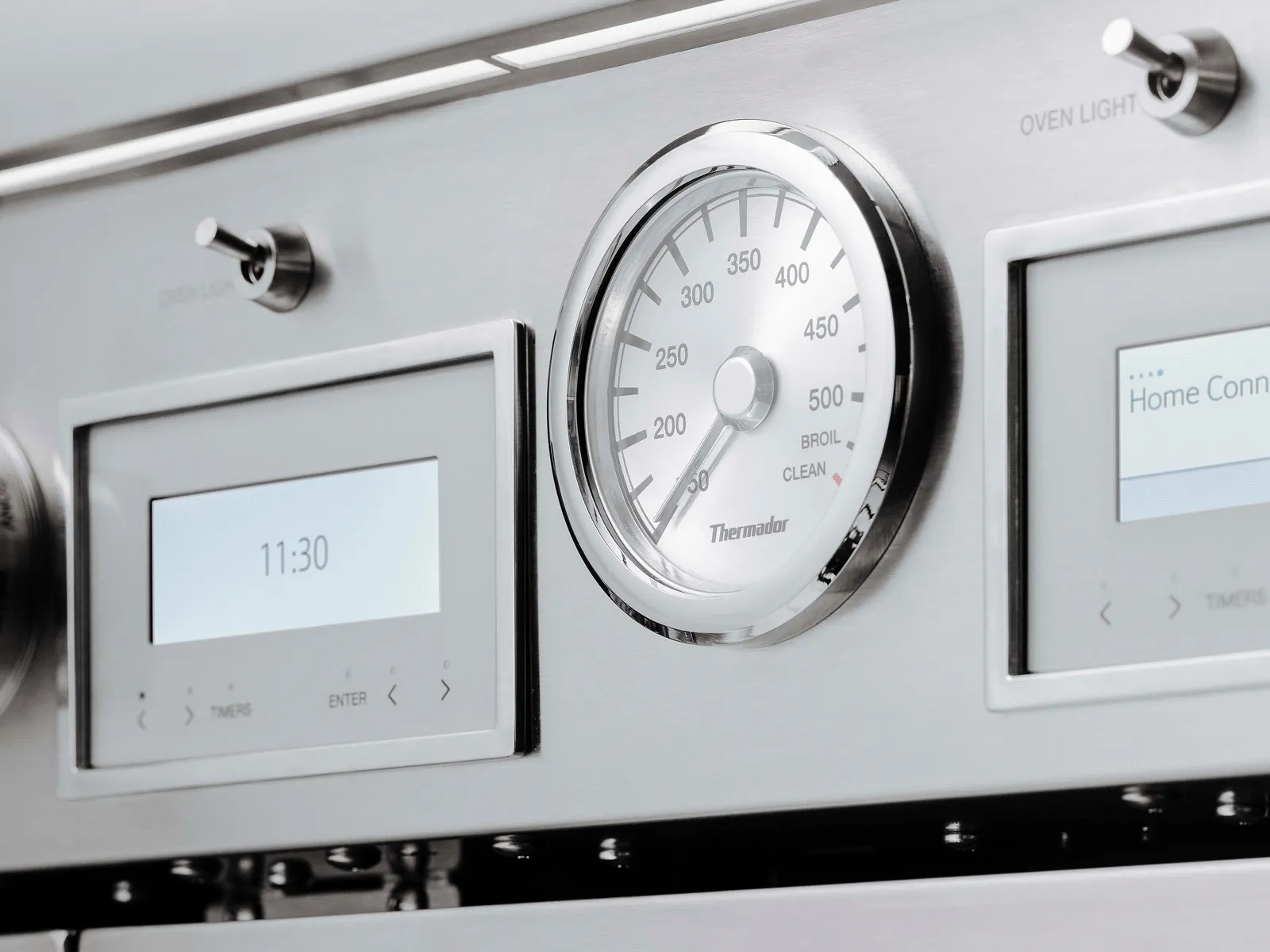 Close-up of a stainless steel oven control panel featuring digital displays, a temperature gauge, and control knobs.