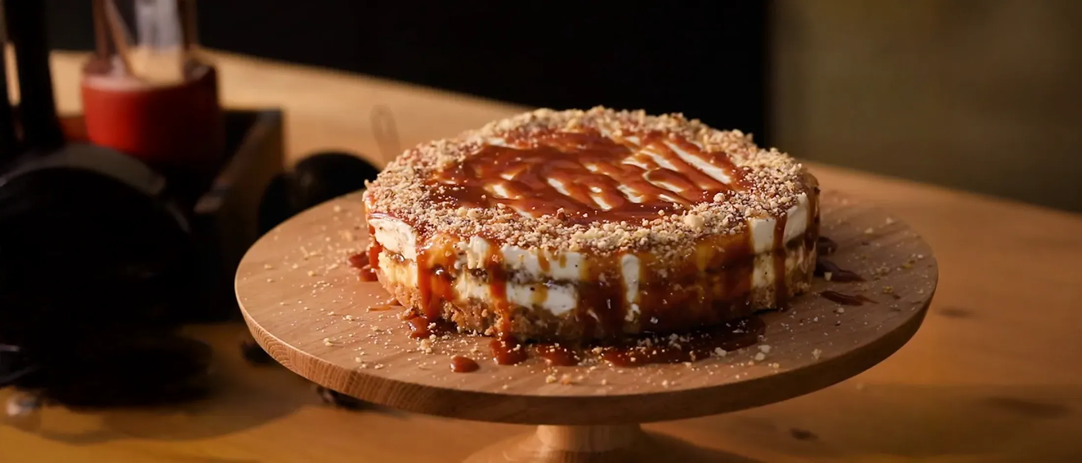 Torta con salsa al caramello e briciole di nocciole su un supporto in legno su un tavolo di legno