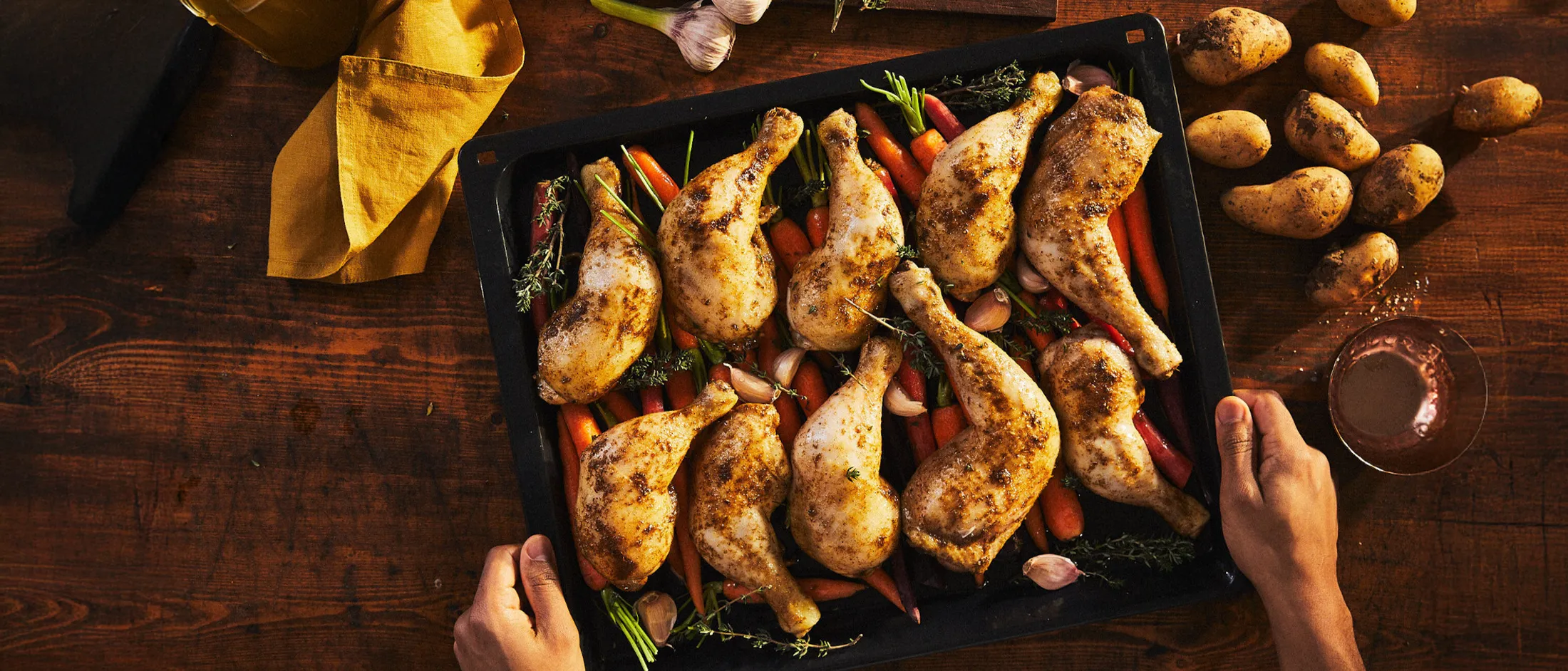 Cosce di pollo arrosto con carote baby e erbe aromatiche in una teglia, ben speziate e dorate.
