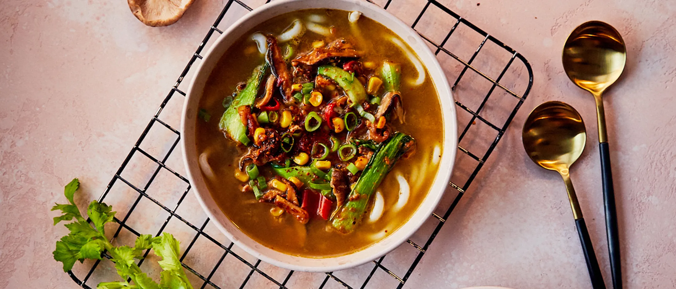 Zuppa di verdure abbondante con spaghetti, spezie e guarnire su uno sfondo rosa.