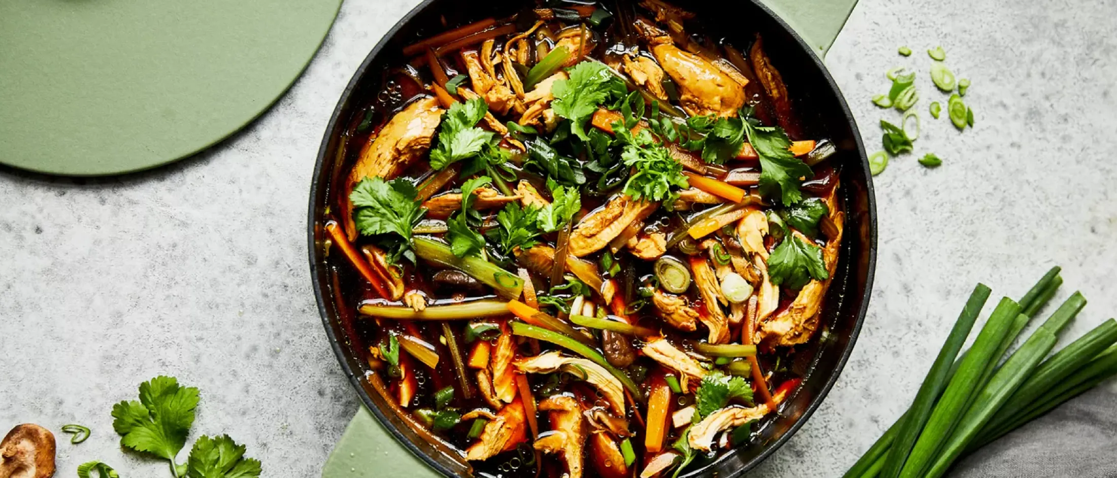 I funghi saltati, i verdi e le erbe in una padella scura su uno sfondo leggero con accenti verdi.