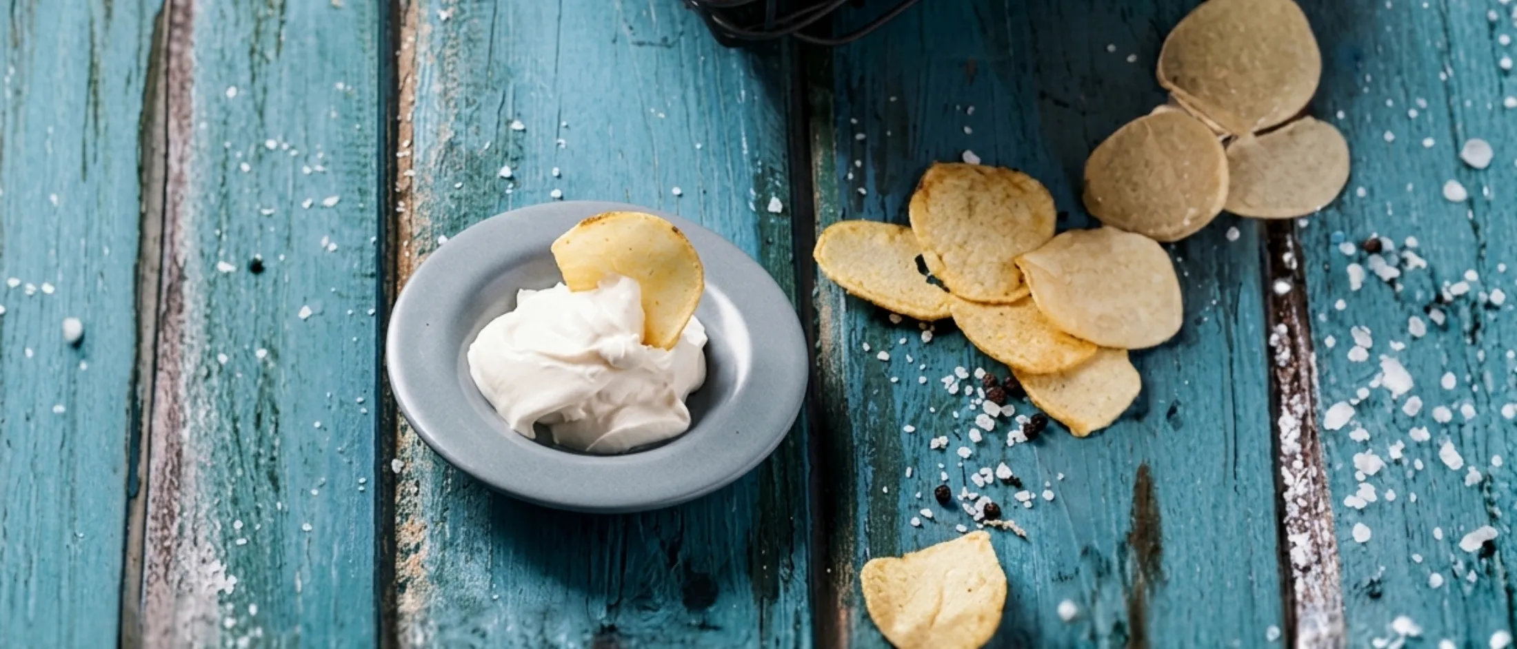 Kartoffelchips mit Dip auf blauem Holztisch.