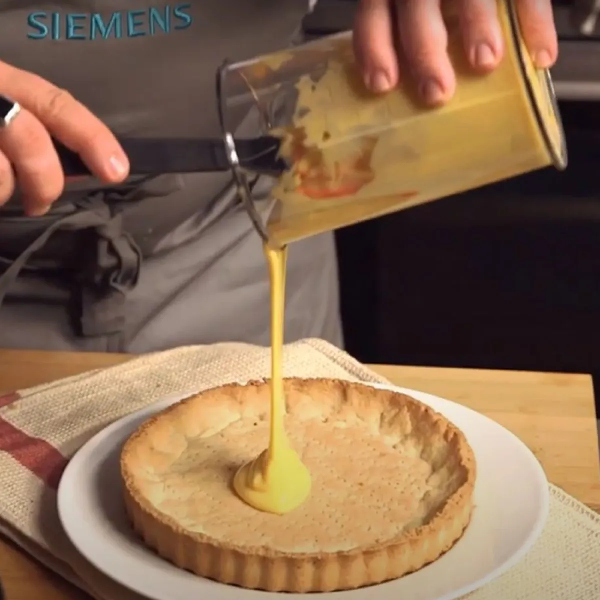 Qualcuno versando crema in una base crostata al forno