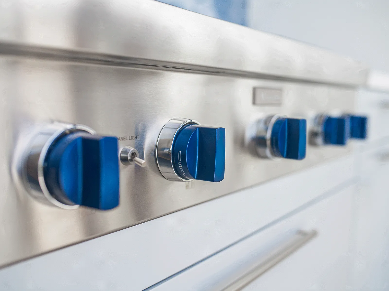 Row of stainless-steel range control knobs with blue rectangular handles.