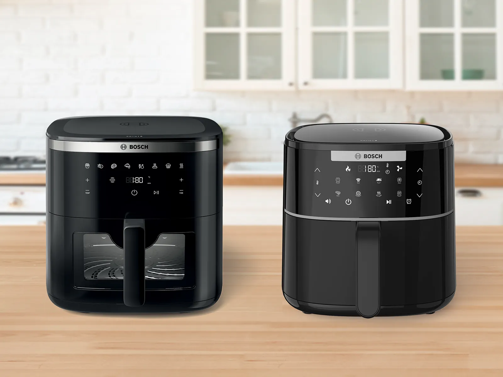 Two Bosch Air Fryer models positioned side by side on a bright kitchen counter. Several plates and bowls of food, including herb bread, chicken, roast, and fries, are placed next to the appliances, showcasing dishes made using the Air Fryers.