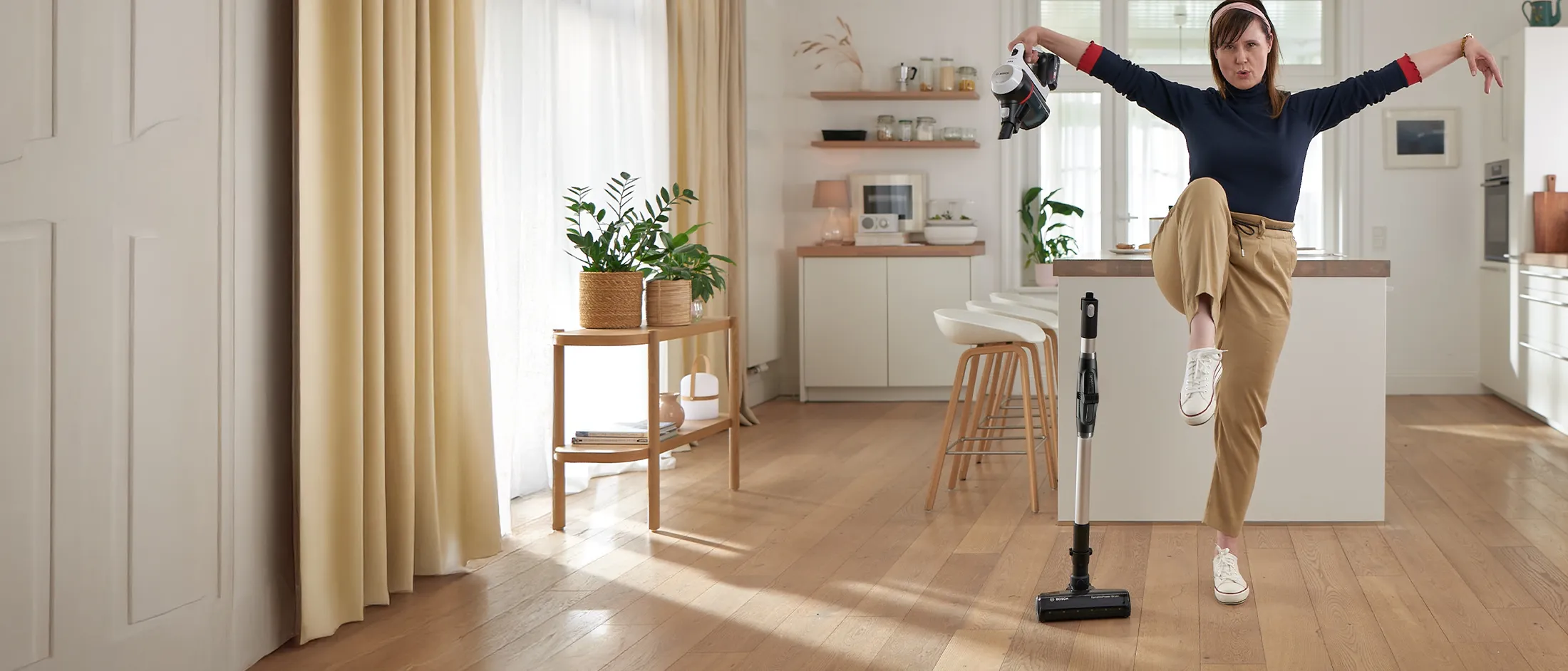 A lineup of four different vacuum cleaners in a bright hallway.