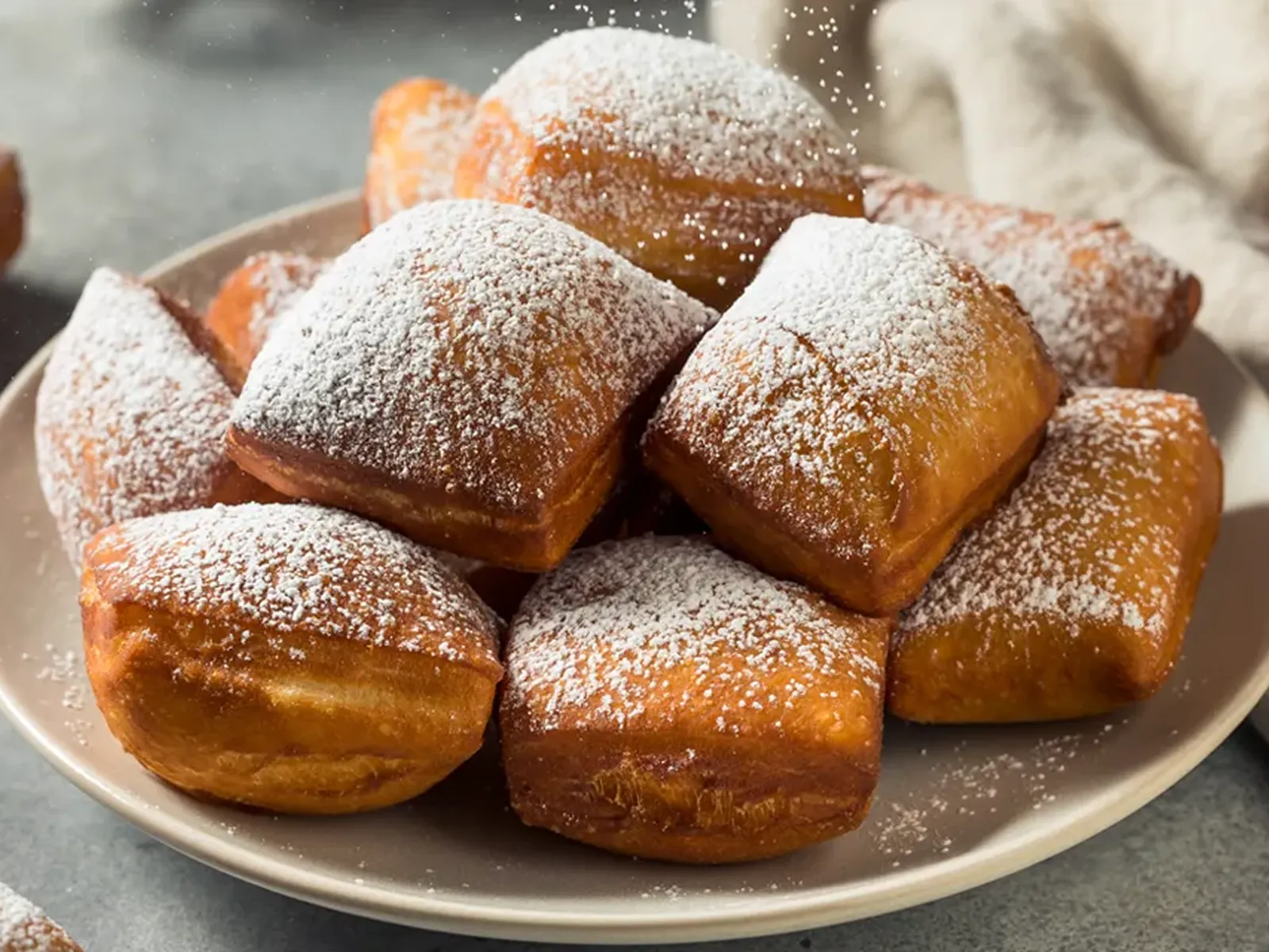 A plate of square beignets dusted with powdered sugar.