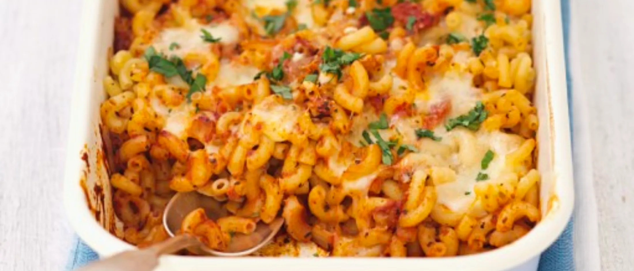 Nudelauflauf mit Tomaten und Mozzarella in einer weißen Auflaufform.