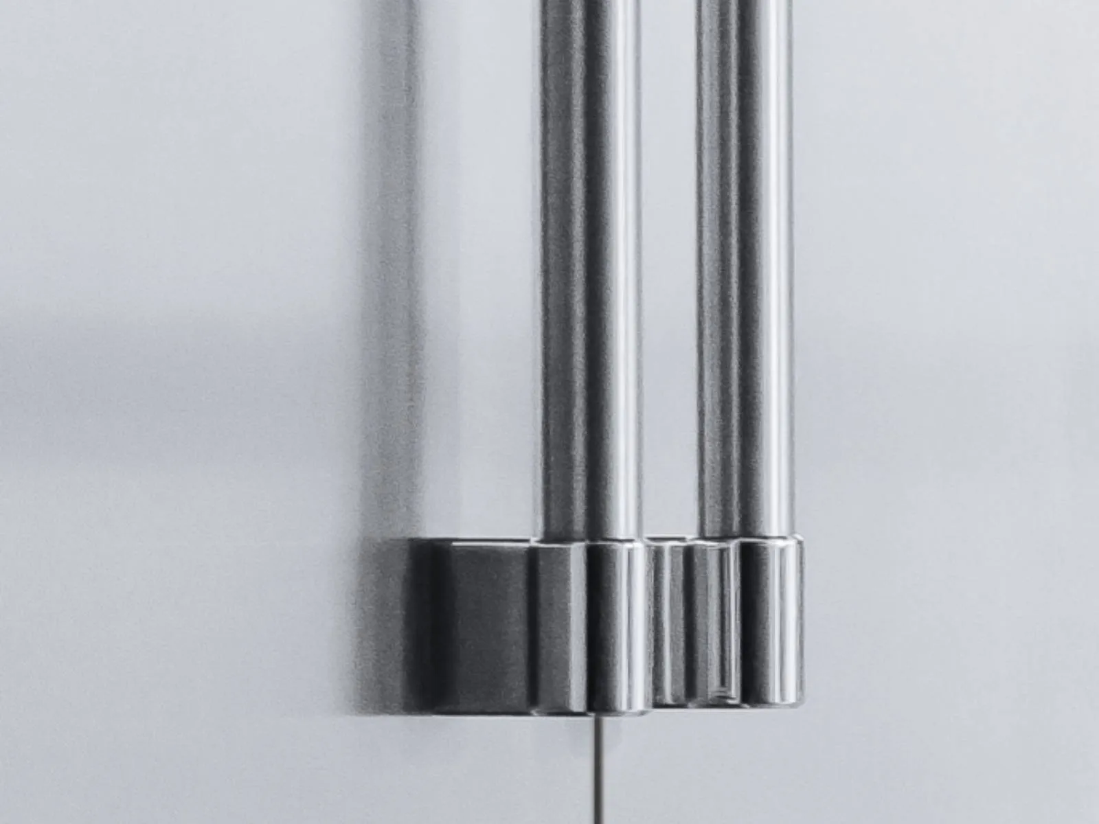 Close-up of sleek stainless steel refrigerator door handles against a smooth, light gray surface.