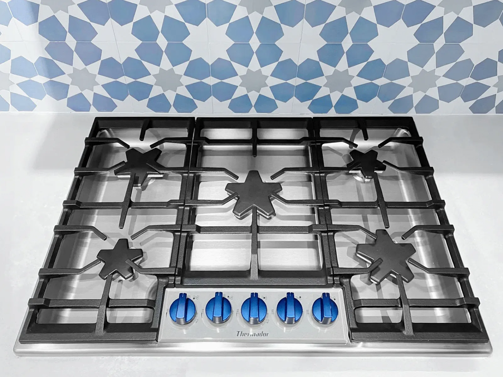 Stainless steel gas range with blue knobs.