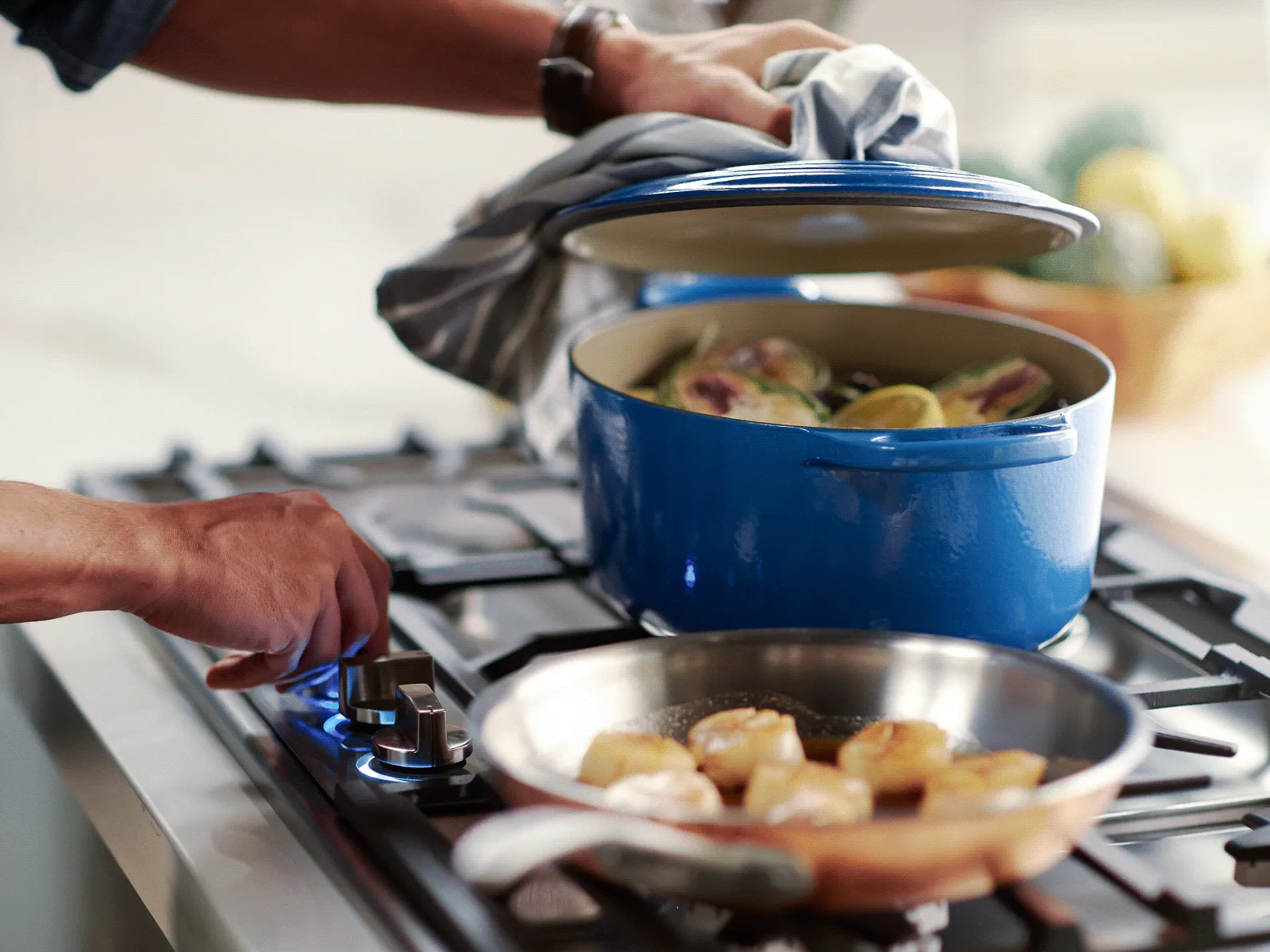 Hands cooking seafood on a stovetop.