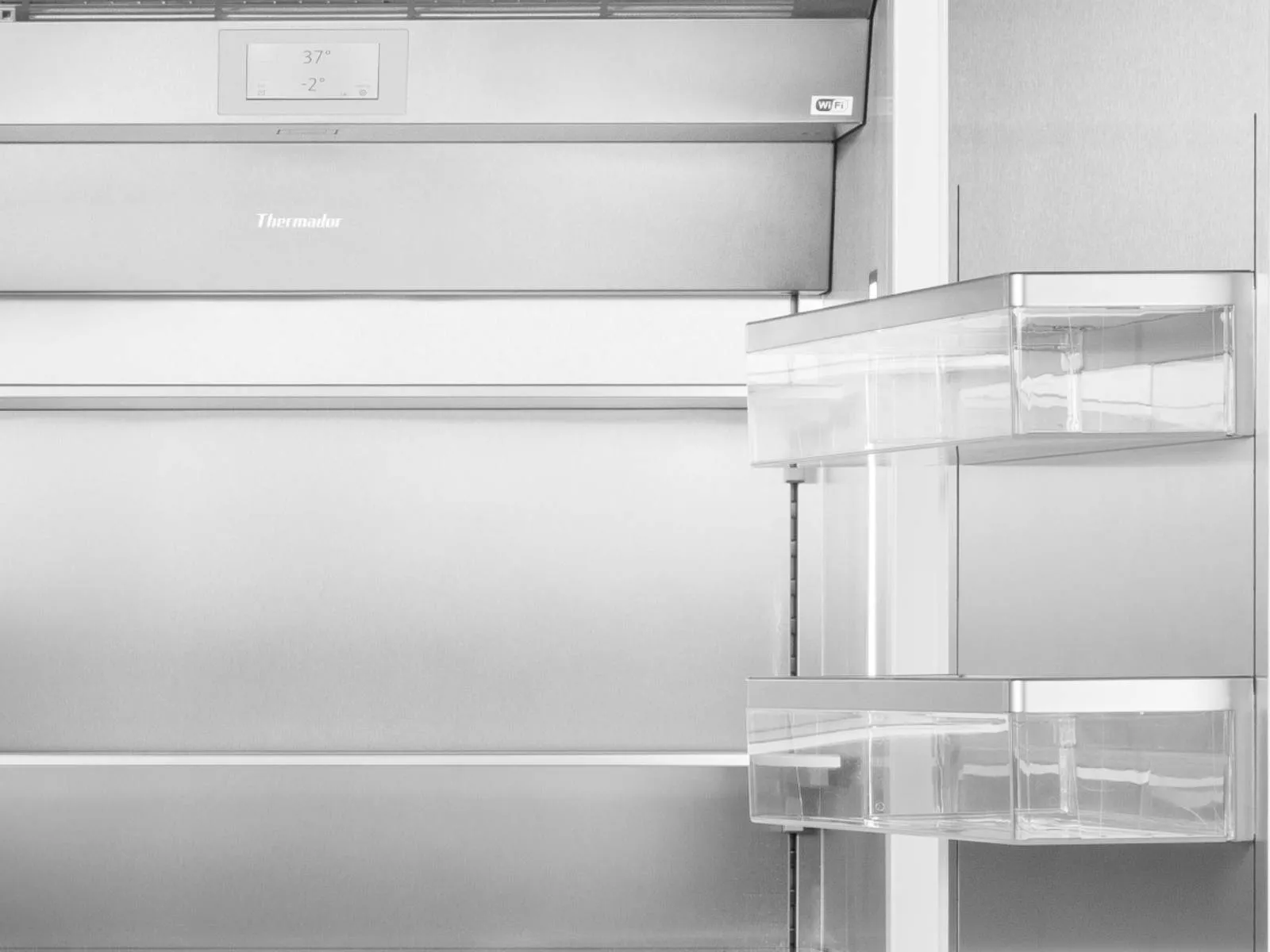Grayscale close-up of an open stainless-steel refrigerator interior showing empty shelves, a digital control panel at the top, and clear plastic door bins
