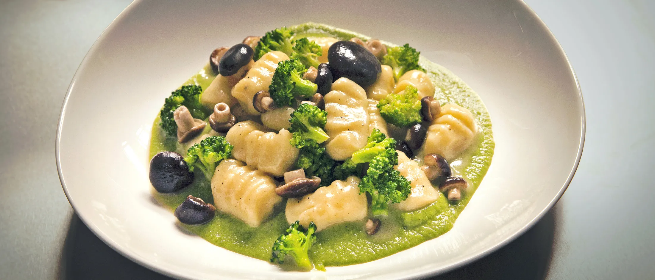 Piatto di verdure saltate, tra cui broccoli, funghi e olive, con tofu cubato