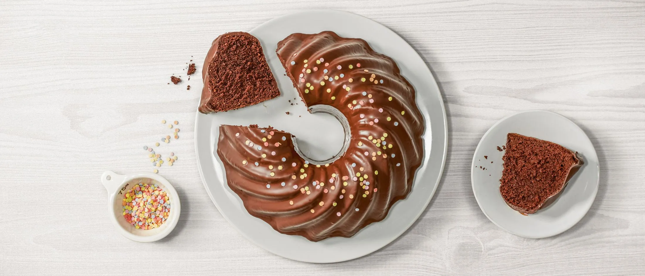 Torta di bundt di cioccolato con cosparse, affettato su piatto con briciole.
