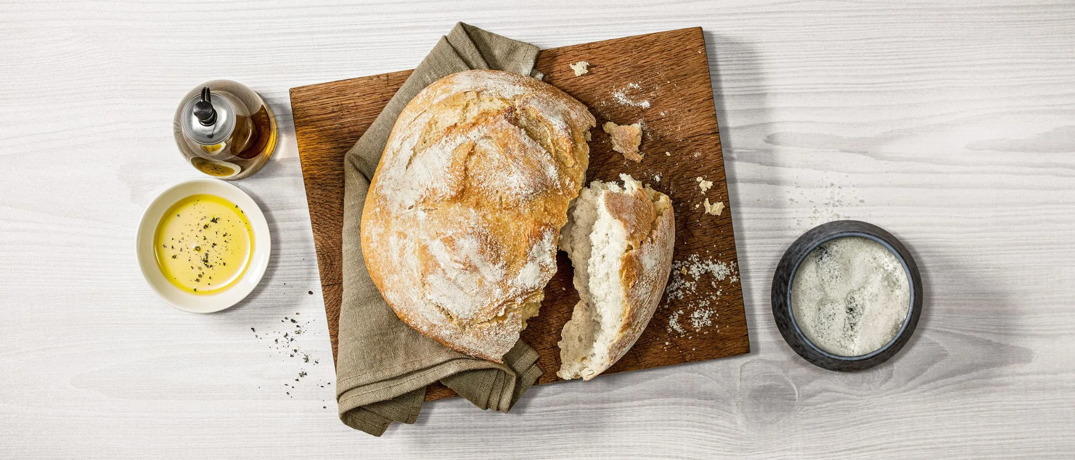 Pane appena sfornato, olio d'oliva e sale su tavola di legno.