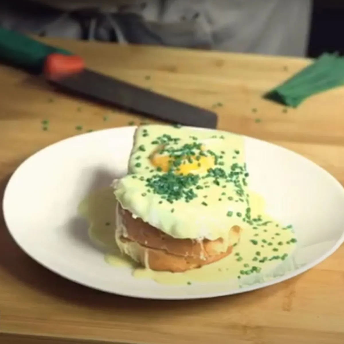Uova su pane tostato con salsa cremosa gialla e erba cipollina tritata su un piatto bianco.