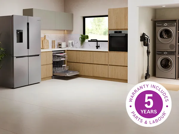 Here's the alt text for each image, Option 1 only:  **Image 1:** A modern kitchen and laundry area featuring a stainless steel French door refrigerator, an open dishwasher, a built-in oven, a wall-mounted cordless vacuum cleaner, and stacked washer and dryer units, with a "5 Years Warranty" badge overlaid.