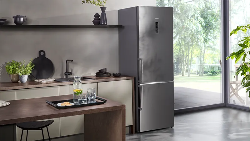  Un réfrigérateur Siemens en pose libre avec une finition en métal mat, dans une cuisine ouverte moderne.