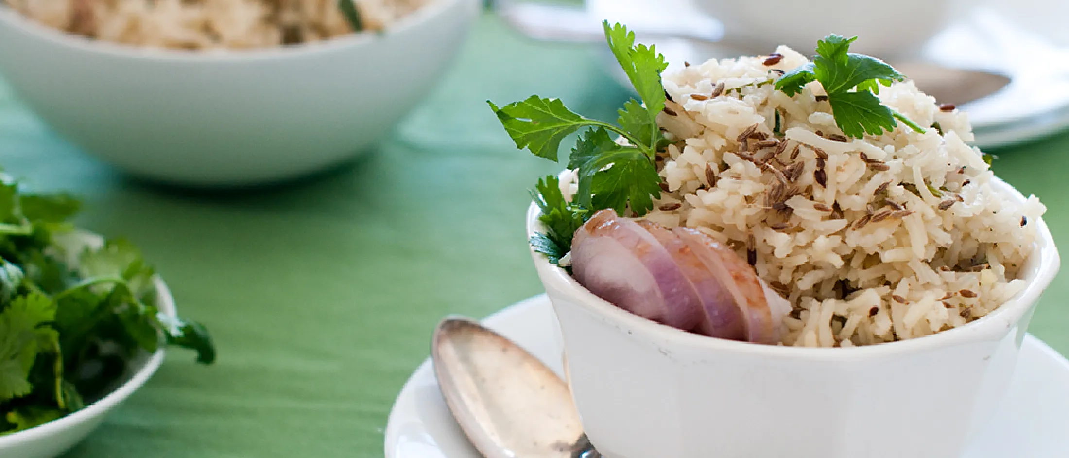 Bowls of cooked rice garnished with parsley, served on a green table