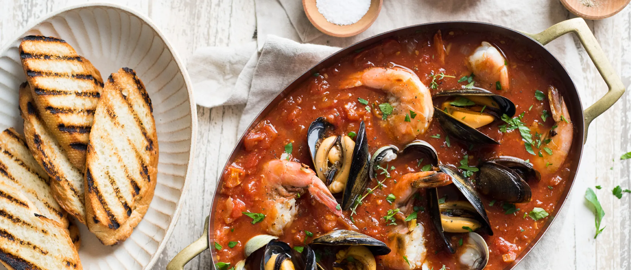 Seafood stew with shrimp and mussels in tomato sauce garnished with herbs.
