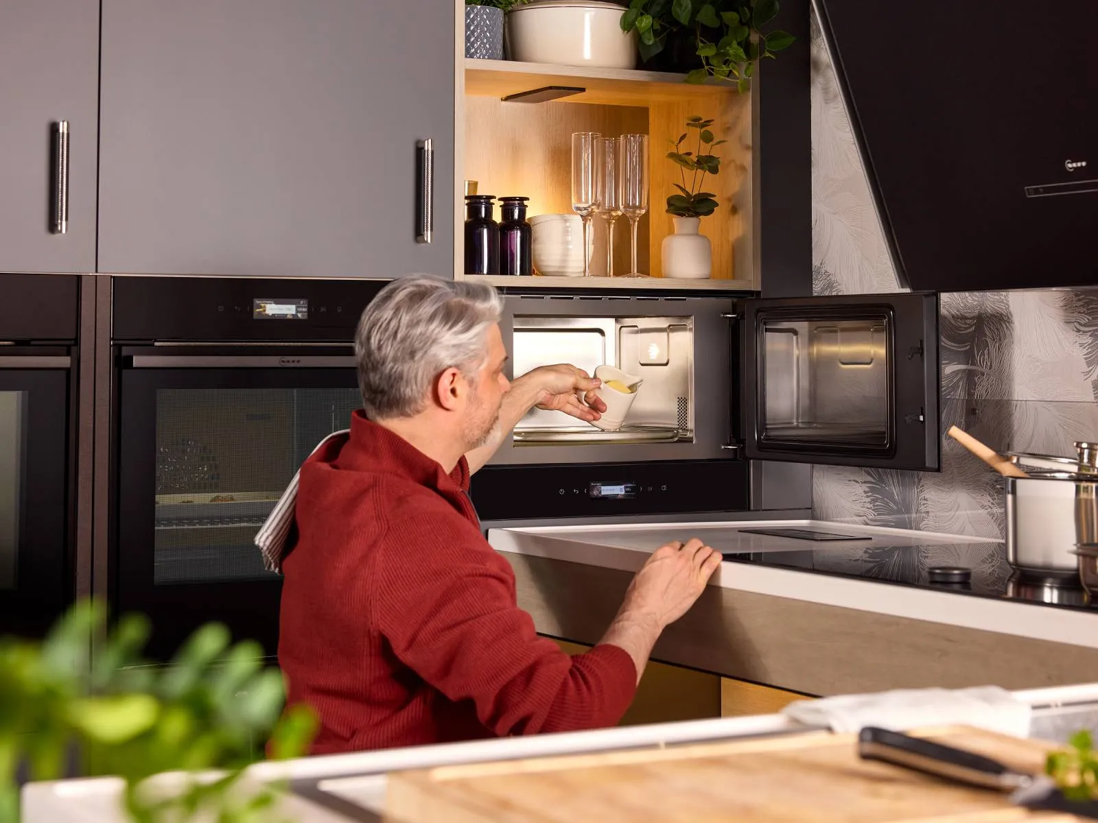 A wheelchair user manoeuvres under the work surface to get closer to a built-in microwave. The door is right-hand hinged for easier access.