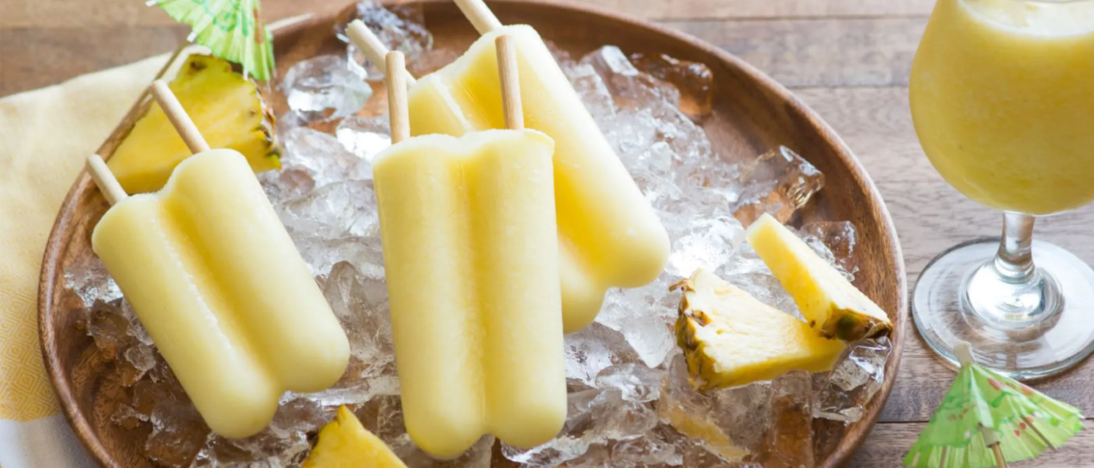 Pineapple popsicles on ice, served with a glass of pineapple juice and tropical garnishes