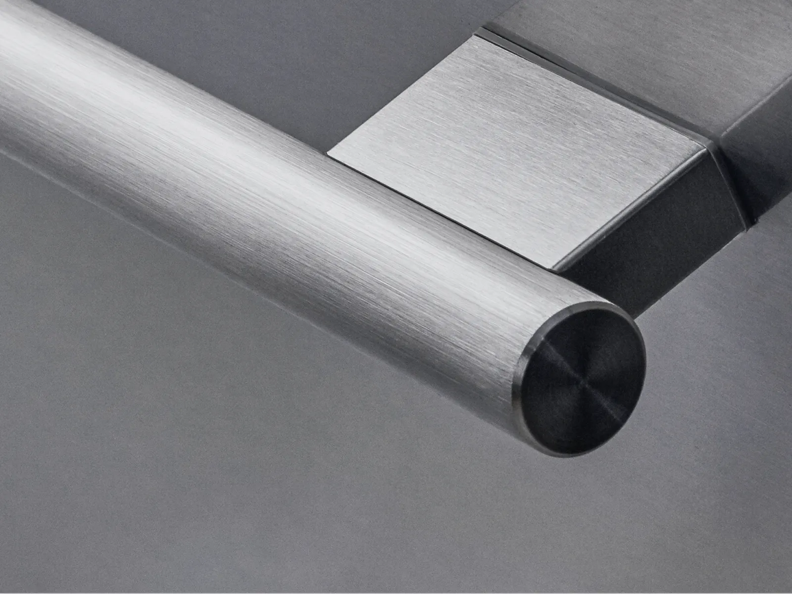 Close-up of a modern stainless steel cylindrical handle with a rectangular mounting base on a gray background.