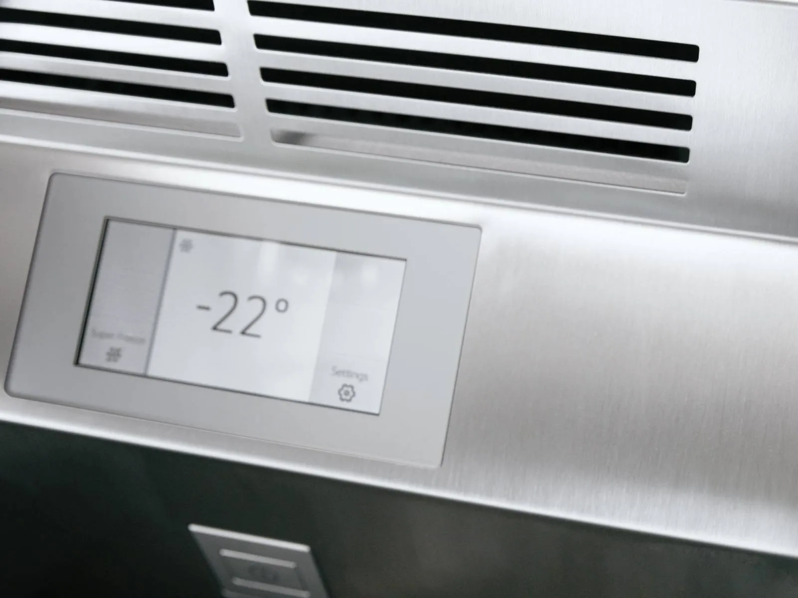 Close-up of a brushed stainless-steel appliance control panel with a touchscreen reading “-22°” beneath horizontal vent slots.