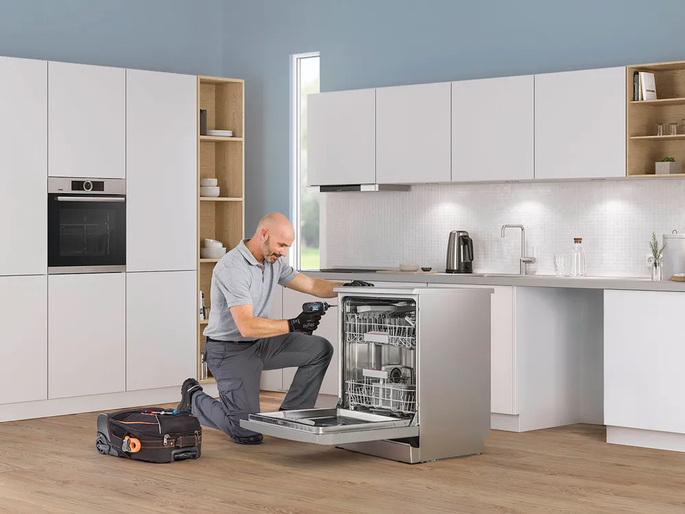 Tehnician Bosch care lucreaza la o mașină de spălat rufe într-o bucătărie