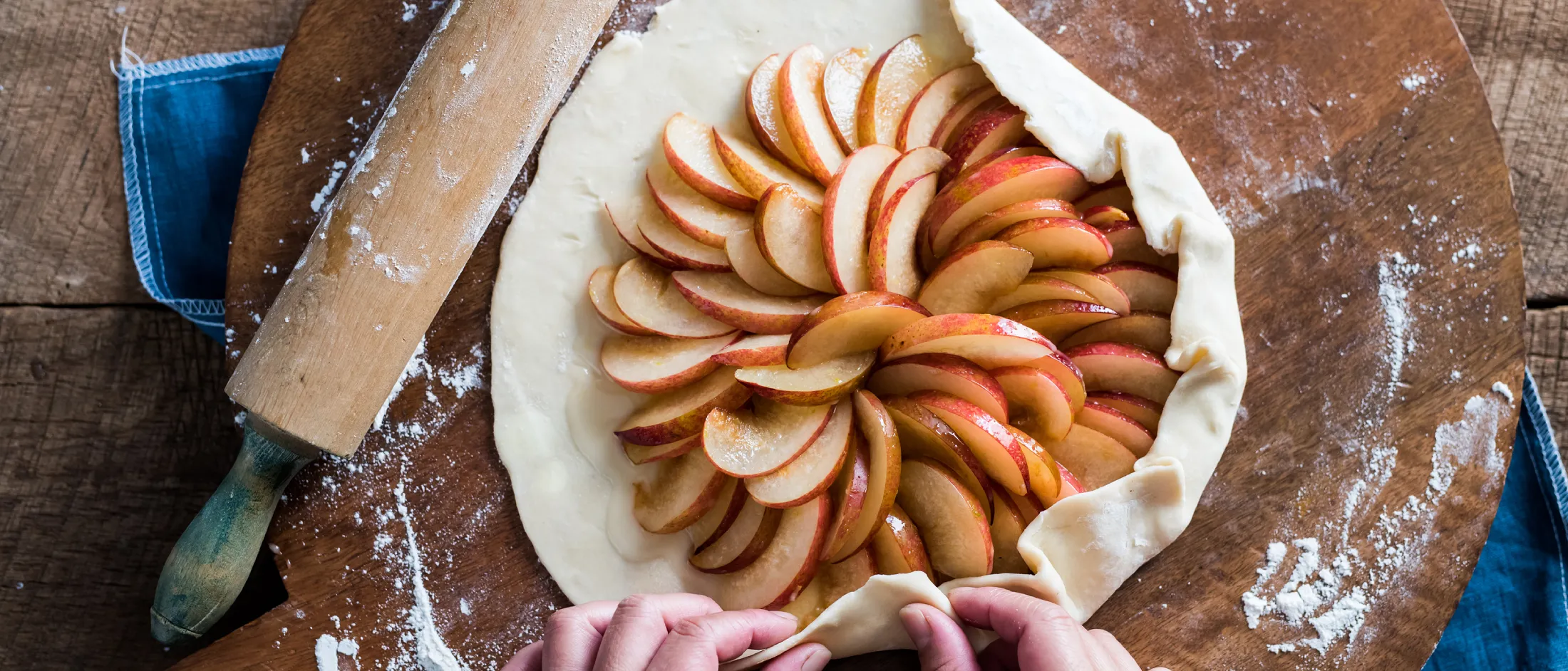 Homemade apple pie with sliced apples arranged in a spiral pattern on a wooden surface.