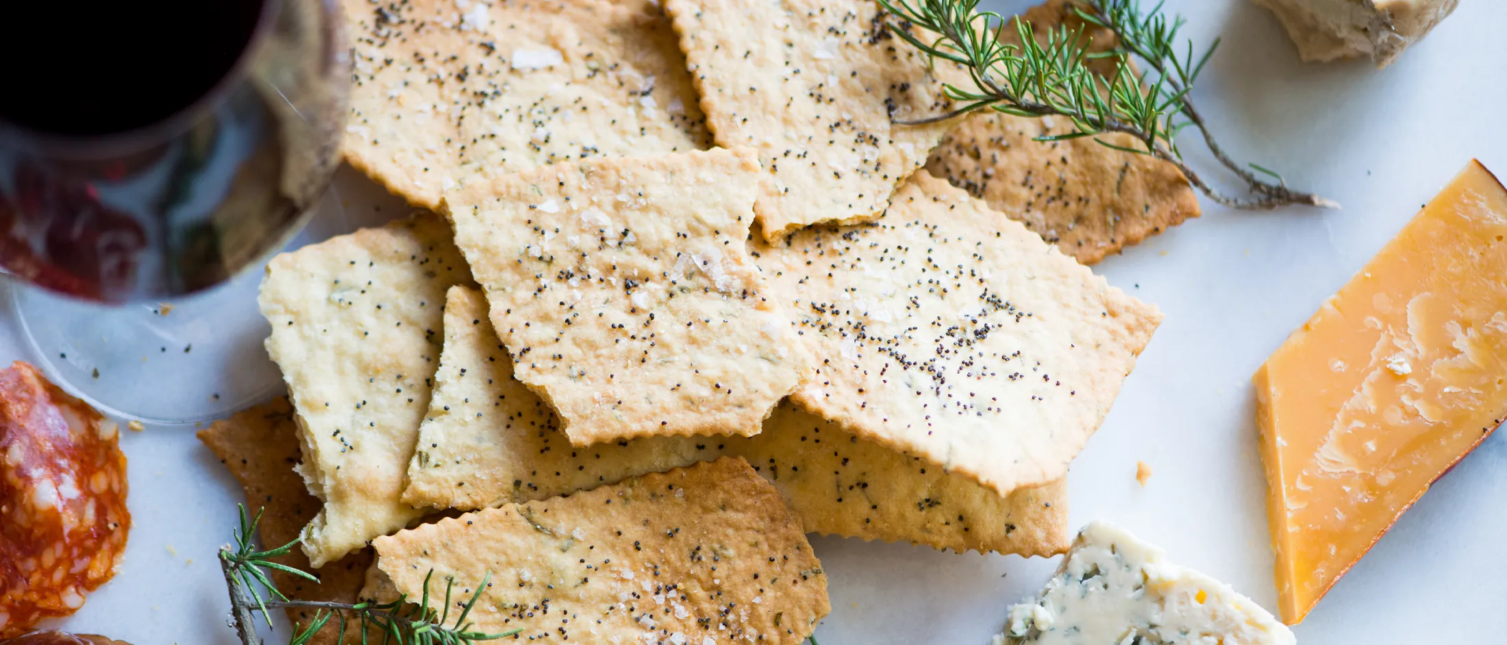 Crackers, cheese, salami, herbs, and wine on a white background - a delightful charcuterie board.