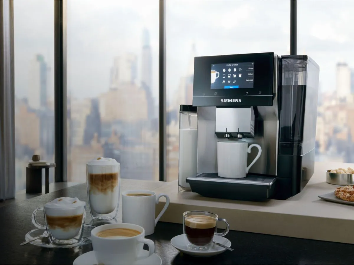 Elegancki ekspres Siemens na drewnianym blacie przygotowuje latte macchiato - obok stoi pojemnik na mleko i dekoracyjna roślina.