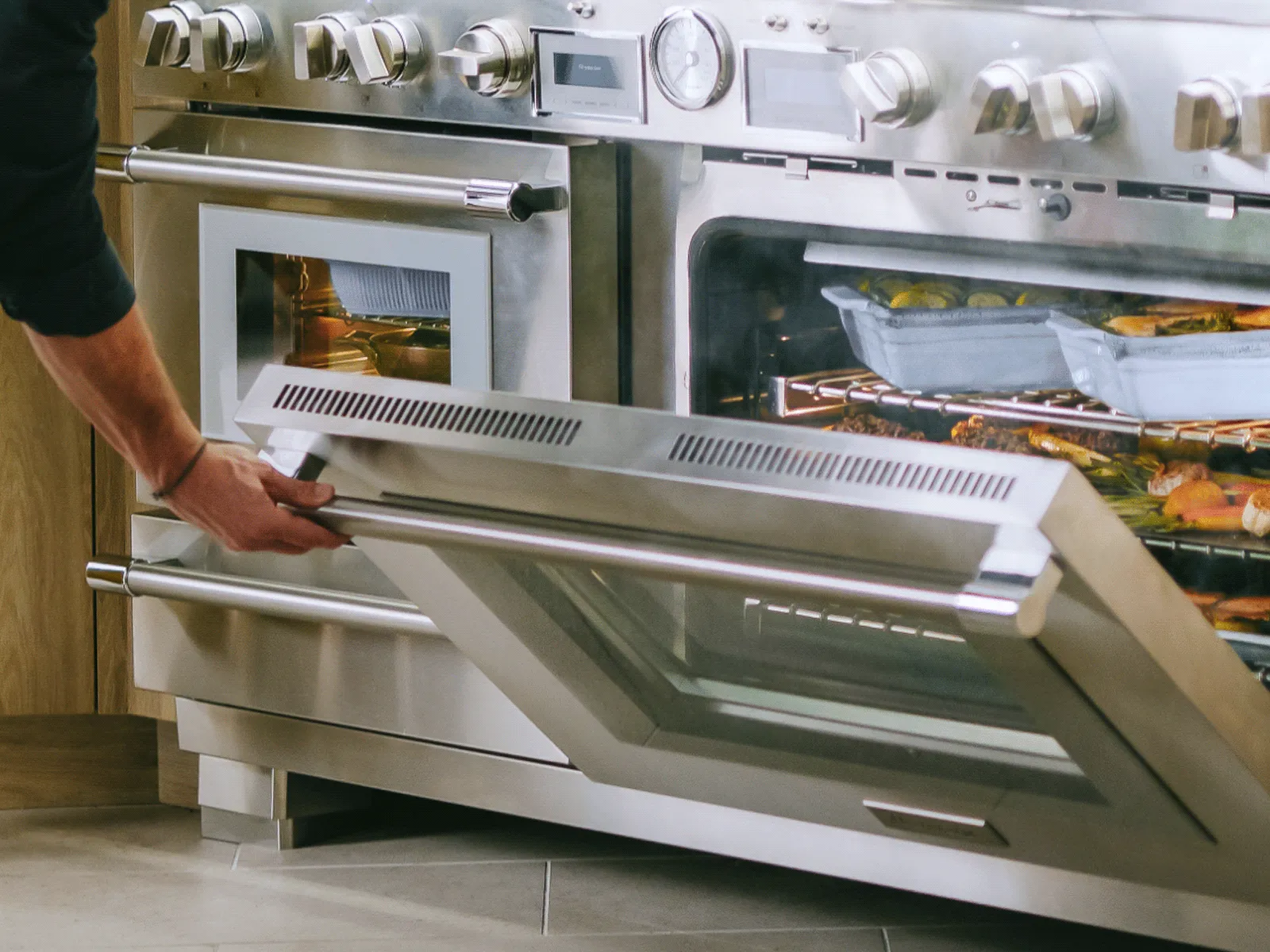 Man closing soft close door on 60 inch pro grand professional dual fuel range with steam