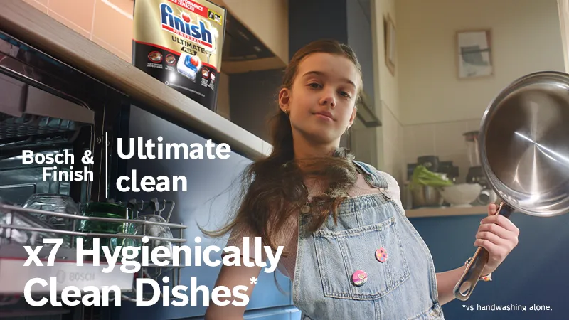 Girl holding pan in front of open dishwasher