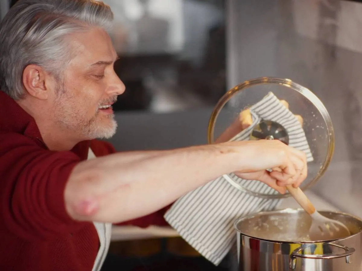Wheelchair user stirs a pot on the hob, with the hood automatically extracting the steam, with hob-to-hood connectivity system activated.